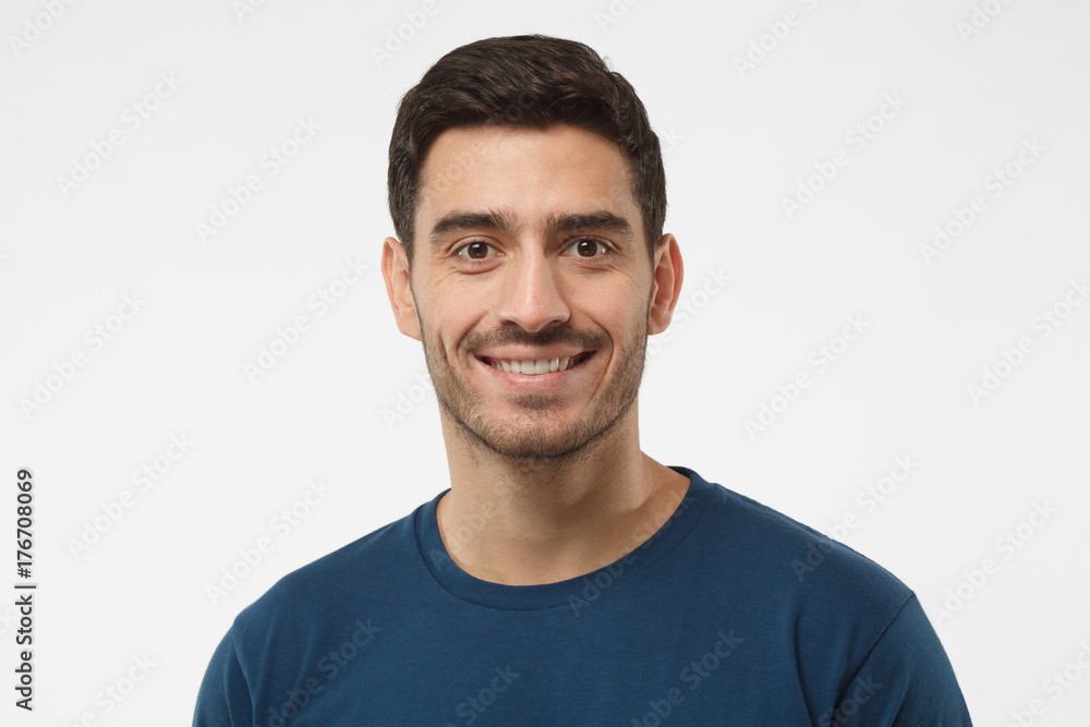 Close up portrait of smiling handsome guy in blue t-shirt isolated on gray background Close up portrait of smiling handsome guy in blue t-shirt isolated on gray background