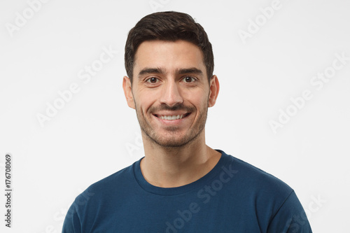 Close up portrait of smiling handsome guy in blue t-shirt isolated on gray background