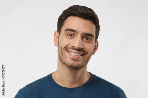 Close up shot of smiling attractive man in blue t-shirt isolated on gray background