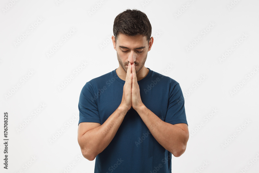 Picture of young guy dressed casually isolated on grey background, having put hands together in prayer or meditation, looking relaxed and calm, dreaming and waiting for all best Picture of young guy dressed casually isolated on grey background, having put hands together in prayer or meditation, looking relaxed and calm, dreaming and waiting for all best