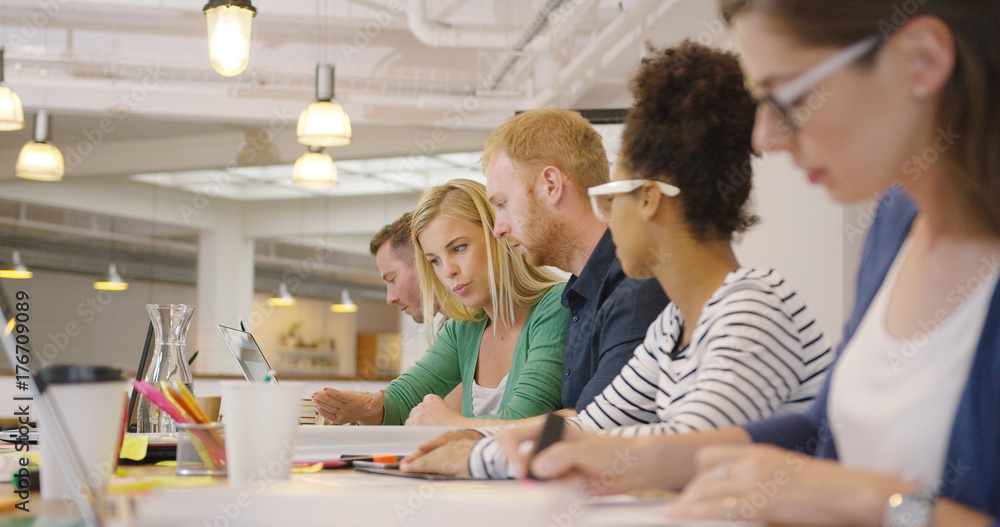 Obraz premium Diverse people posing in row at table on background of modern office and working all together with various documents.
