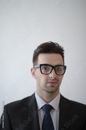 Portrait of a young and fashion businessman with nerd glasses on gray