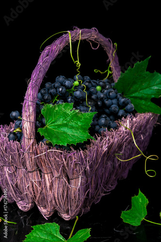 Red wine grapes in voiolet basket on bllack background. photo