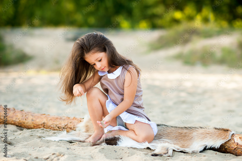 beautiful little girl on the beach playing with sand and having fun. beautiful little girl on the beach playing with sand and having fun.