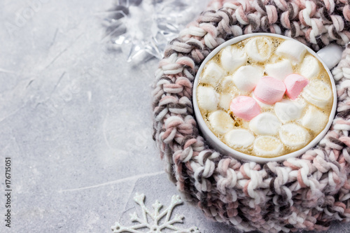 Winter marshmallow hot chocolate in a mug with warm knitted scarf. Selective focus, space for text, close up. 