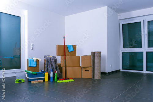 Helle, leere Luxuswohnung mit Kartons, Reinigungsmitteln und zusammen gerollten Teppich
