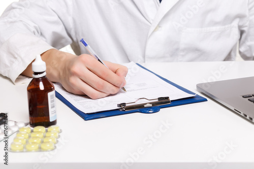 Close-up of doctor s hands writing prescription and holding bottle with pills. Healthcare  medical and pharmacy concept.