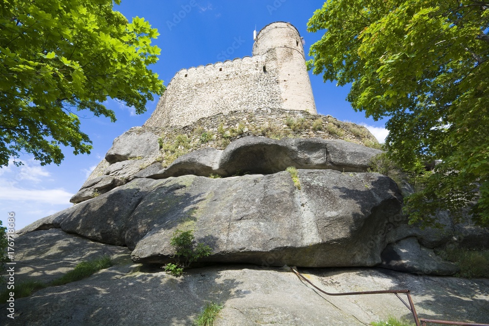 Ruins of medieval Chojnik castle situated on the top of high rock against blue sky in Jelenia Gora, Poland