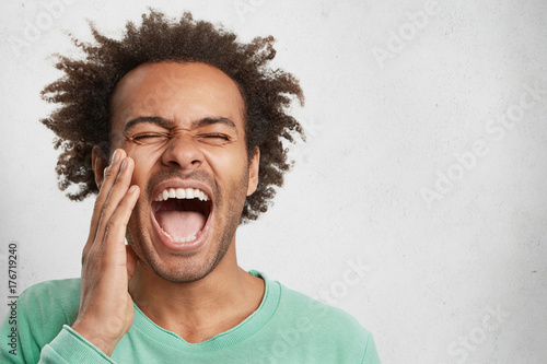 Overjoyed excited happy mixed race man openes mouth wide, closes eyes, screams joyfully, being glad to become father firstly, rejoice birth of sun or daughter, isolated over white background photo