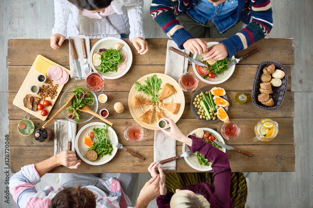 Top view of four people eating delicious food at festive dinner table