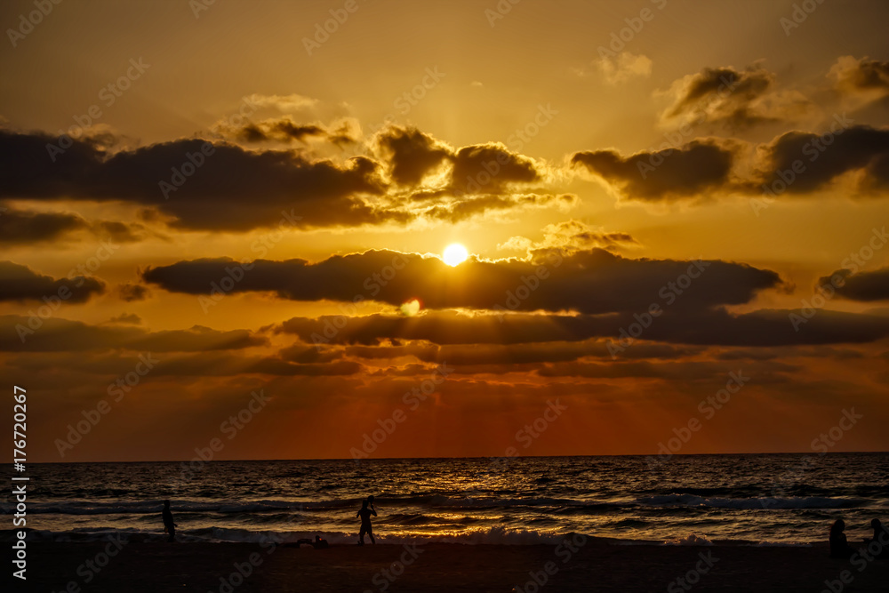 Colorful sunset on the Mediterranean with silhouettes of people on the beach Colorful sunset on the Mediterranean with silhouettes of people on the beach