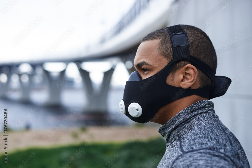 Profile picture of self-determined confident young African athlete wearing  black training mask to increase load on breathing muscles during morning  cardio workout routine outdoors. Sports and fitness Stock Photo | Adobe  Stock