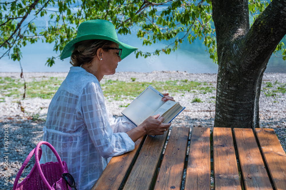Woman reading book sitting on a table by lake