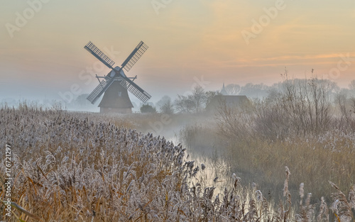 Wooden windmill in hazy landscape photo
