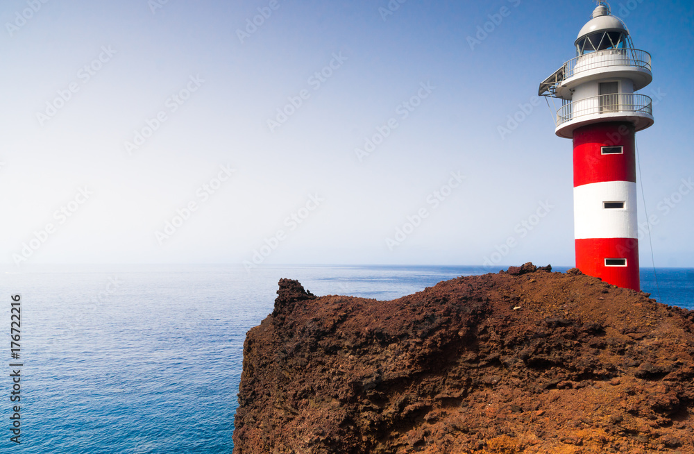 typical red and white lighthouse on the rock cliff in Tenerife Island, Spain