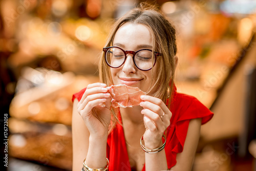 Photography Young woman in red dress eating jamon traditional spanish dry-cured ham sitting