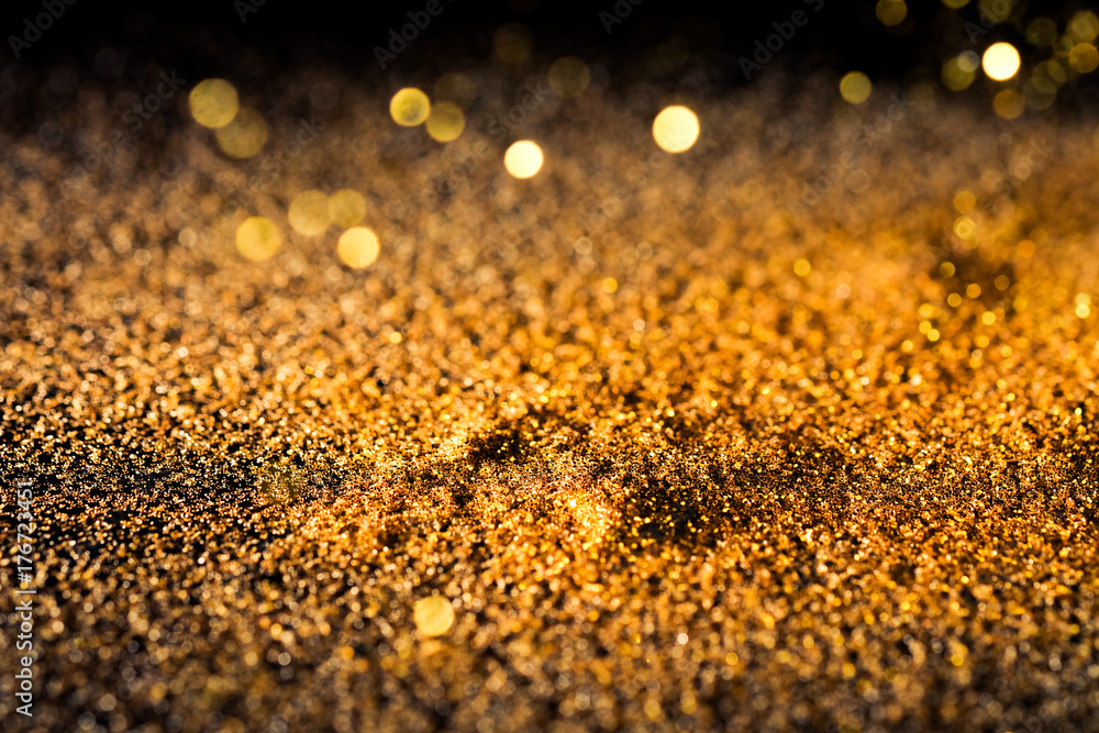 Sprinkle gold shiny dust on a black background with copy space