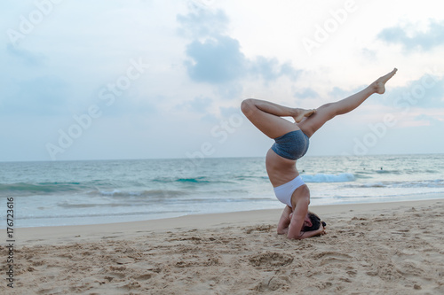 Natural looking pregnant woman practicing yoga at the seashore at sunset © Maygutyak
