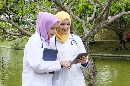 medical and healthty lifestyle concept,young muslimah doctor standing and having discussion at park during lunch hour. photo