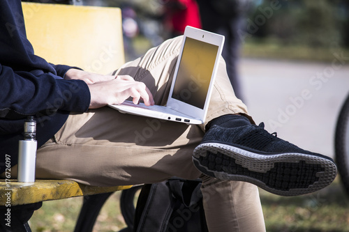 Teenager outdoors in town working laptop 