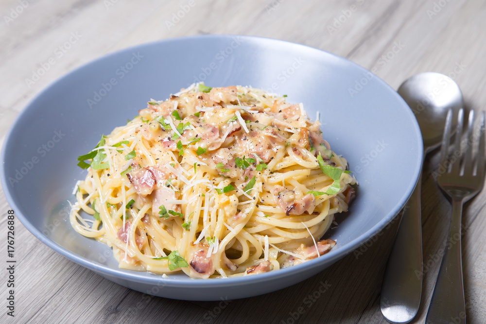 Pasta carbonara with bacon, cheese and parsley. Traditional Italian dish. Close-up, selective focus.