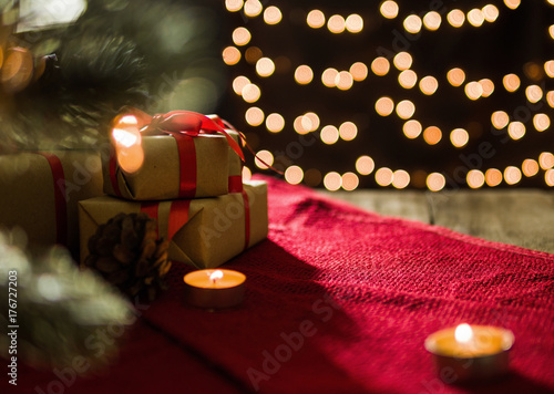 Christmas gift boxes on red scarf and candle on bokeh lights background. photo