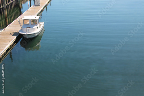 Single, smal boat docked near a wooden pier © Robin Keefe