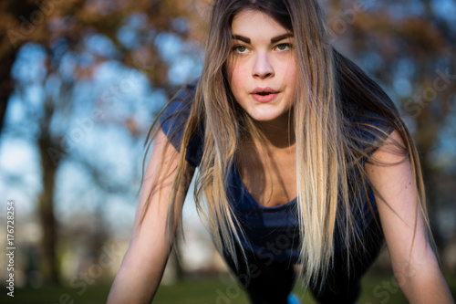 Close-up of young woman doing push ups and exercising at park