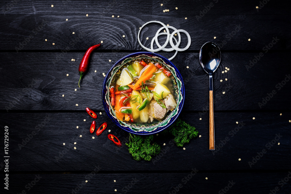Naklejka Zupa shurpa w talerzu z orientalnym ornamentem na drewnianym tle. Kuchnia środkowoazjatycka. Widok z góry