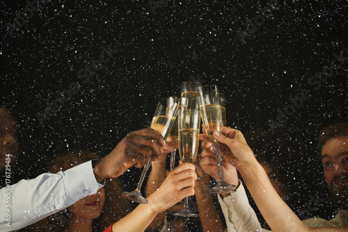 Fototapeta Group of young people celebrating new year with champagne at night club