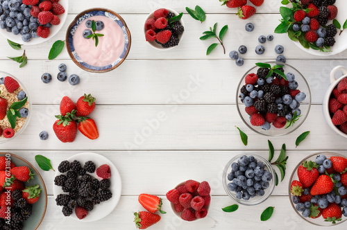 Healthy breakfast with berries and yogurt on white wooden table