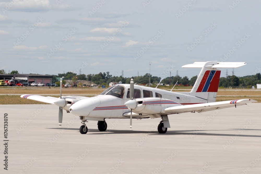 red white and blue dual propeller aircraft stationary on the airport tarmac