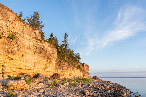 Sunset on the beach. Limestone cliff in the sea under blue sky and white clouds. Kesselaid, a small island in Estonia. Nordic countries, Europe