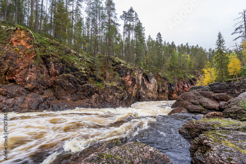 Fototapete Red cliff, stone wall, forest, waterfall and wild river view in autumn