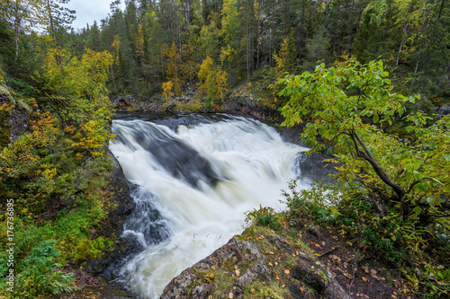 Cliff, stone wall, forest, waterfall and wild river view in autumn. Fall colors - ruska time in Myllykoski. One part of Karhunkierros Trail. Oulanka National Park in north Finland. Lapland, Europe