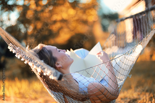 Beautiful girl in hammock reading a book