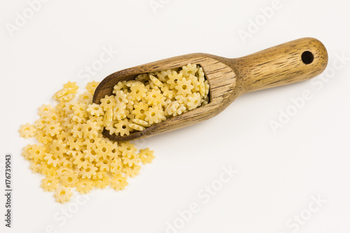 raw pasta shaped like little stars on a wooden scoop