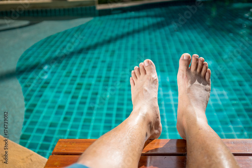 The foot of the men who sit near the pool in the resort at Pattaya. Thailand on weekend