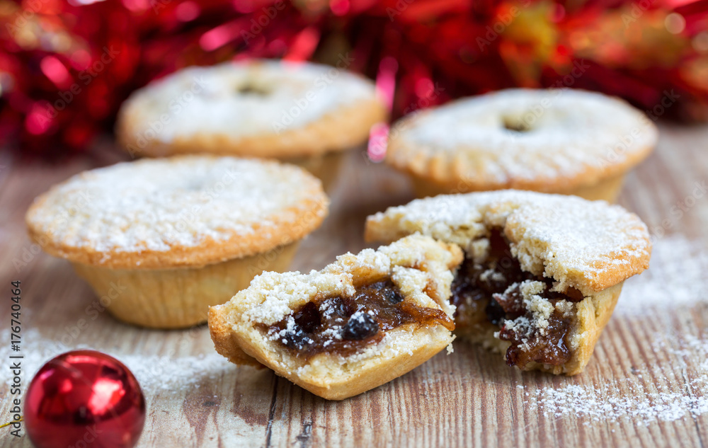 Fototapeta premium Closeup of an open mince pie on a wooden table with red christmas background