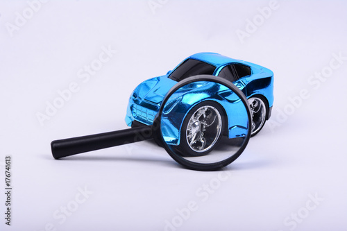 Isolated metallic blue toy car on white background. Magnifying glass focus on tyre sport's rim.