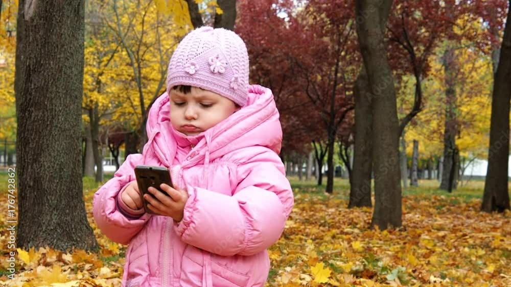 Little girl with phone in autumn park. Little girl with phone in autumn park.