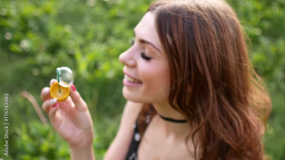 Girl blowing soap bubbles. Young beautiful woman sits on the grass in the park and plays with bubbles. Slow motion video. Girl blowing soap bubbles. Young beautiful woman sits on the grass in the park and plays with bubbles. Slow motion video.