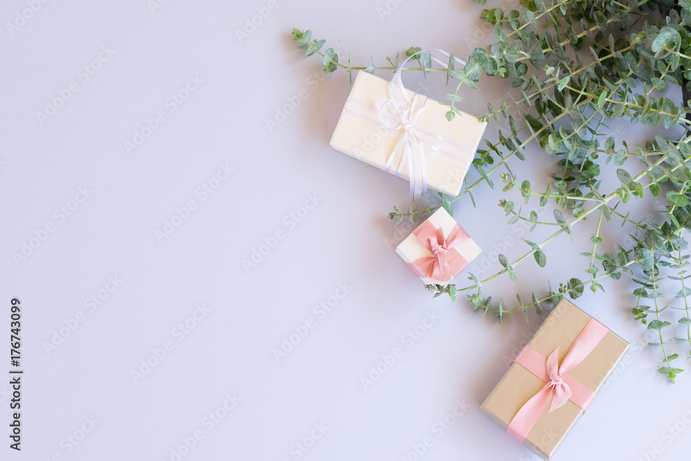 Green leaves with gift boxes on blue background from above with copy space, flat lay scene Green leaves with gift boxes on blue background from above with copy space, flat lay scene