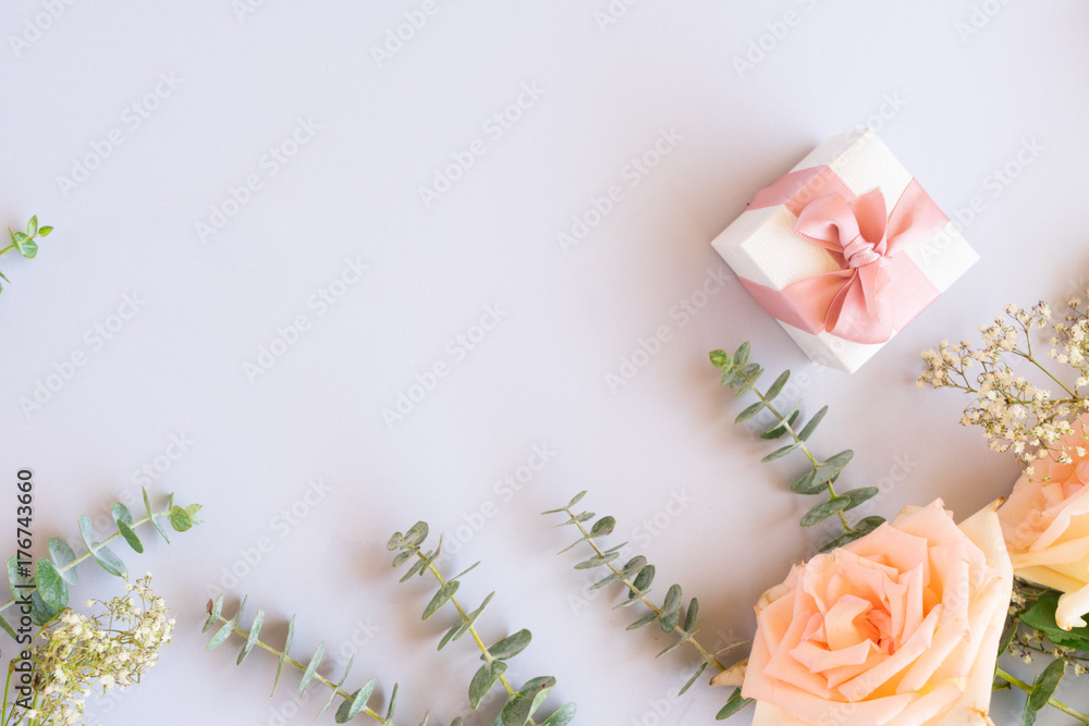gift or present box and fresh rose flowers on blue table from above