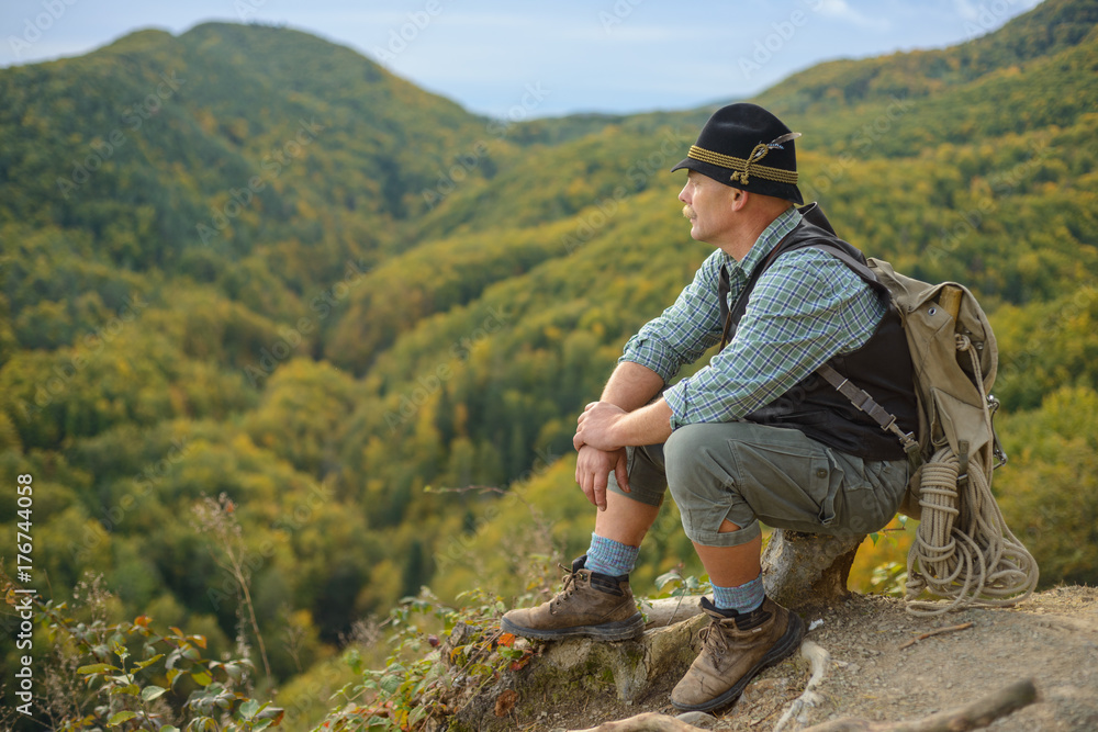 Naklejka premium An old man in the outdoors in the mountains. Senior man on top of the mountain. 