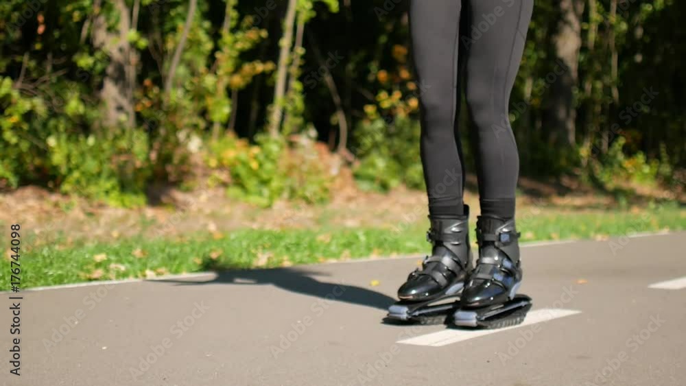 Young beautiful girl doing sports in the park. A woman jumps on special shoes for fitness. Young beautiful girl doing sports in the park. A woman jumps on special shoes for fitness.