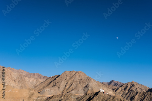 Landscape mountain image with the moon in clear blue sky background
