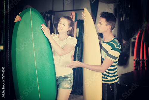 Happy male is showing to female the surfboard