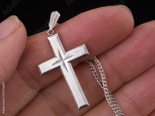 Silver cross and chain in hand, Christian jewelry symbol.