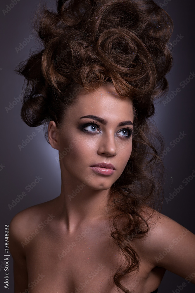 Fototapeta premium Portrait of a beautiful girl with a creative high hairstyle and makeup.